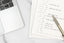 A self-reflection notepad next to a computer on a white table