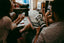 Two people sit together talking while looking at a phone and a magazine