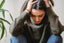 A woman looks down, holding her head, looking stressed