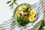 A plated lunch with a poached egg on a white and gray tablecloth