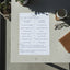Sheet of paper with handwritten text on a table with a cup and glasses.